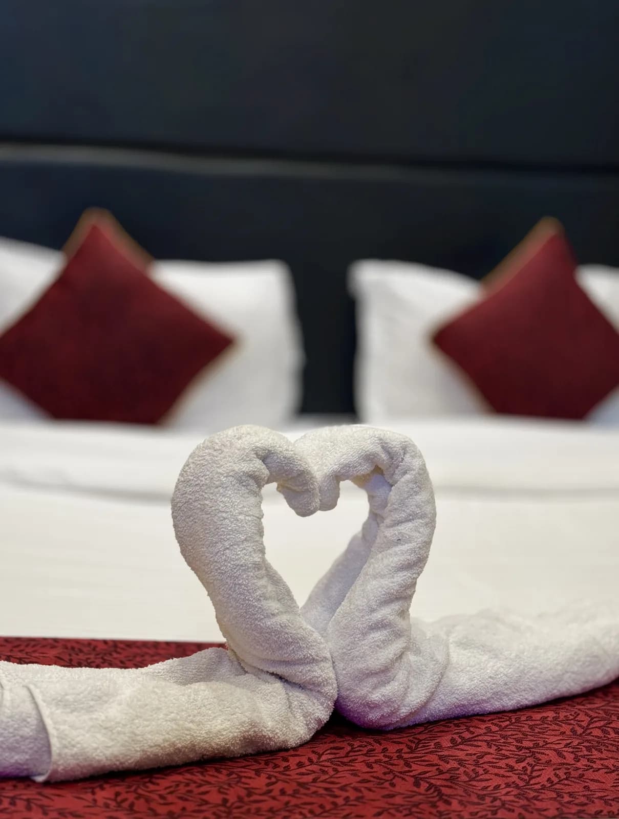 Towels folded into two swans forming a heart on a guest bed at Hotel Gulmarg House